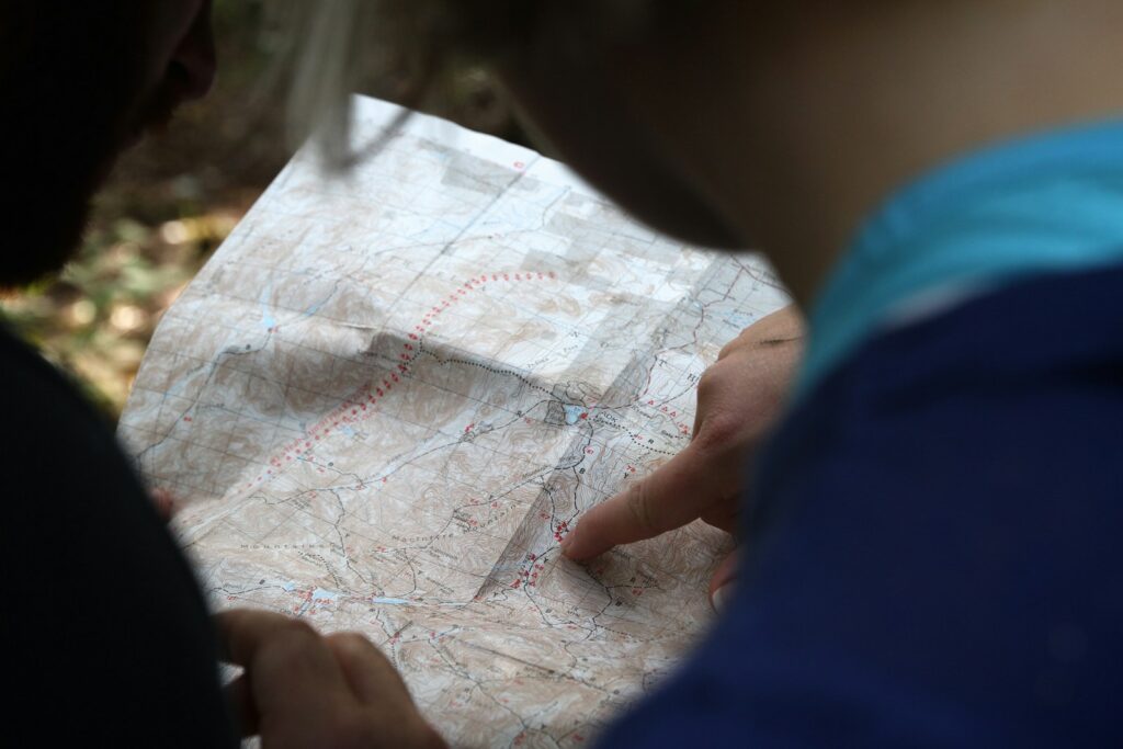 person pointing on beige map - NAVIGATE: Consulting Services